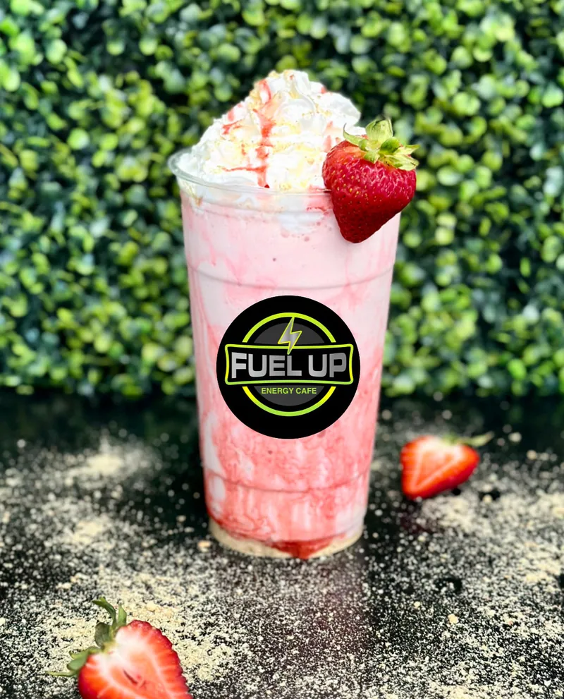 A pink strawberry shake with whipped topping and a fresh strawberry