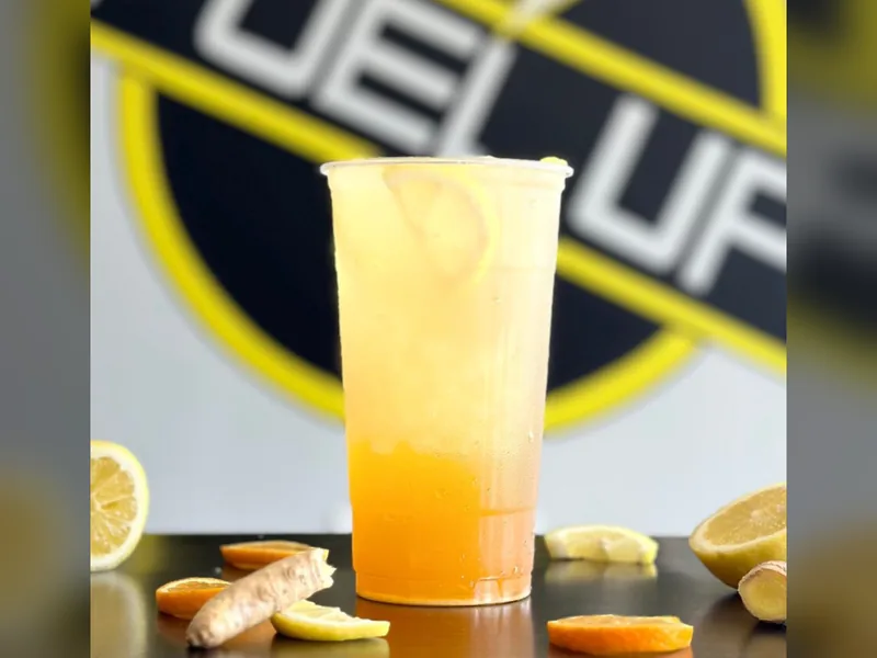 Immunity wellness tea with lemon slices in front of the Fuel Up logo wall at Fuel Up Energy Cafe in Bolingbrook, IL
